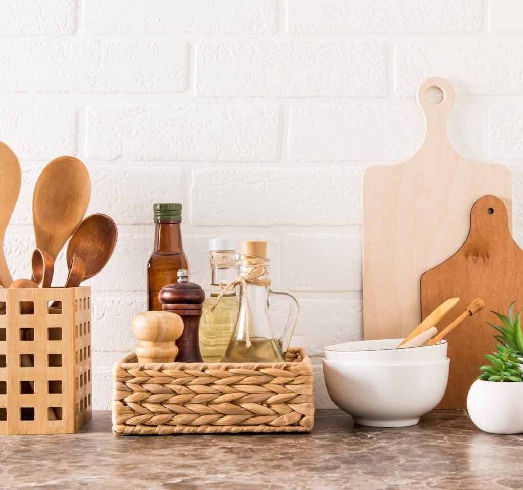 stylish-white-kitchen-background-with-kitchen-utensils-and-green-potted-house-plants-on-a-marble-cou